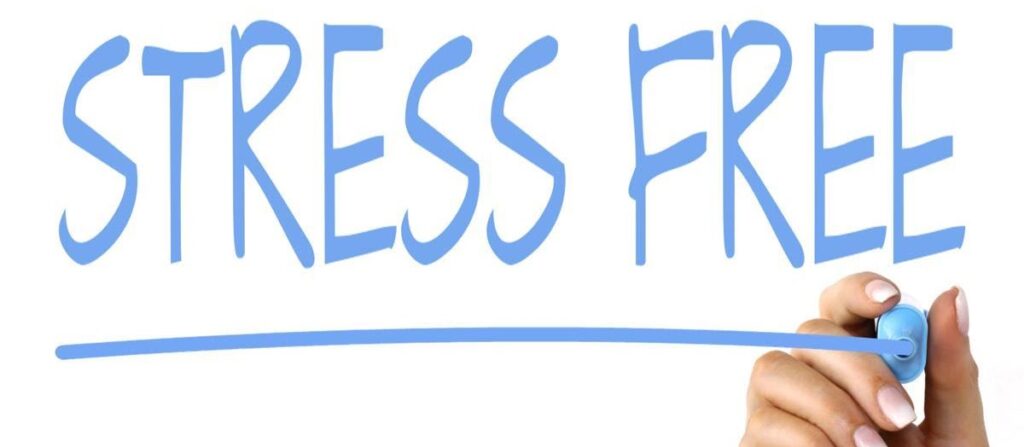 Hand underlining the words Stress Free written in blue marker.