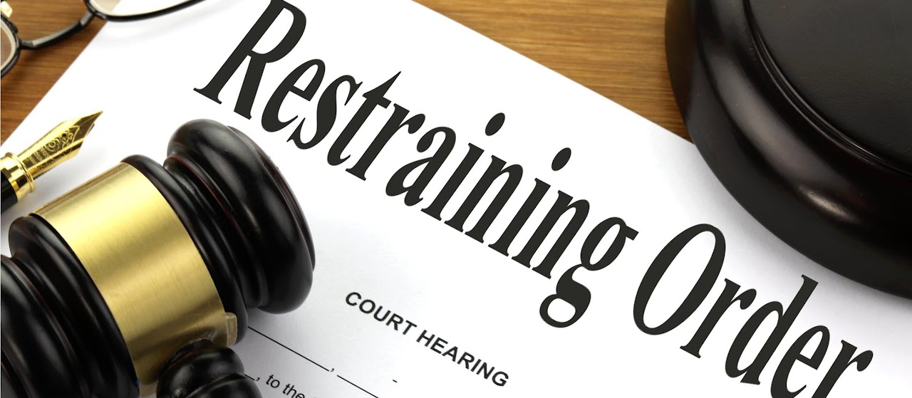 Legal document titled Restraining Order next to a gavel and glasses.