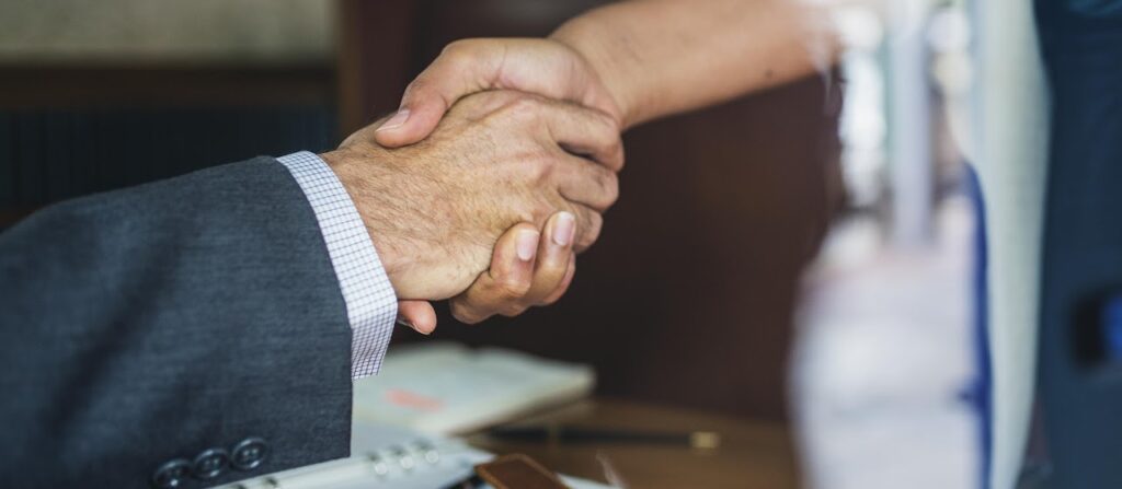 Close-up of two people in suits shaking hands.