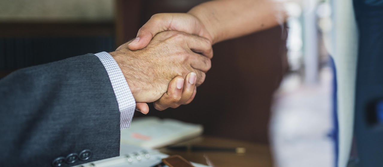 Close-up of two people in suits shaking hands.