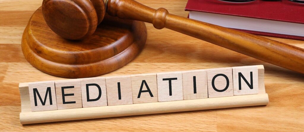 Wooden tiles spelling MEDIATION next to a judge's gavel.