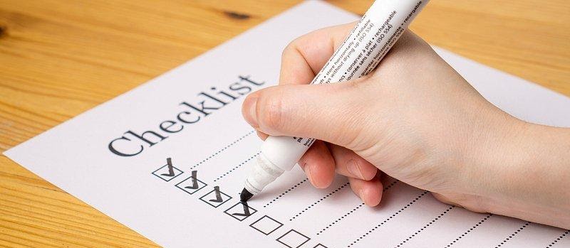 Hand marking a checkbox on a document titled Checklist.