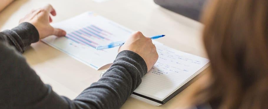 A person reviewing legal documents and charts with a pen in hand.